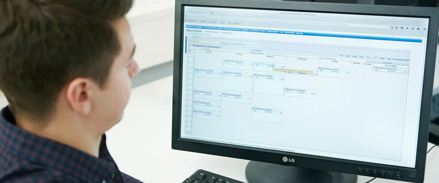 Ein Studierender schaut sich an einem Computer einen Stundenplan an. 